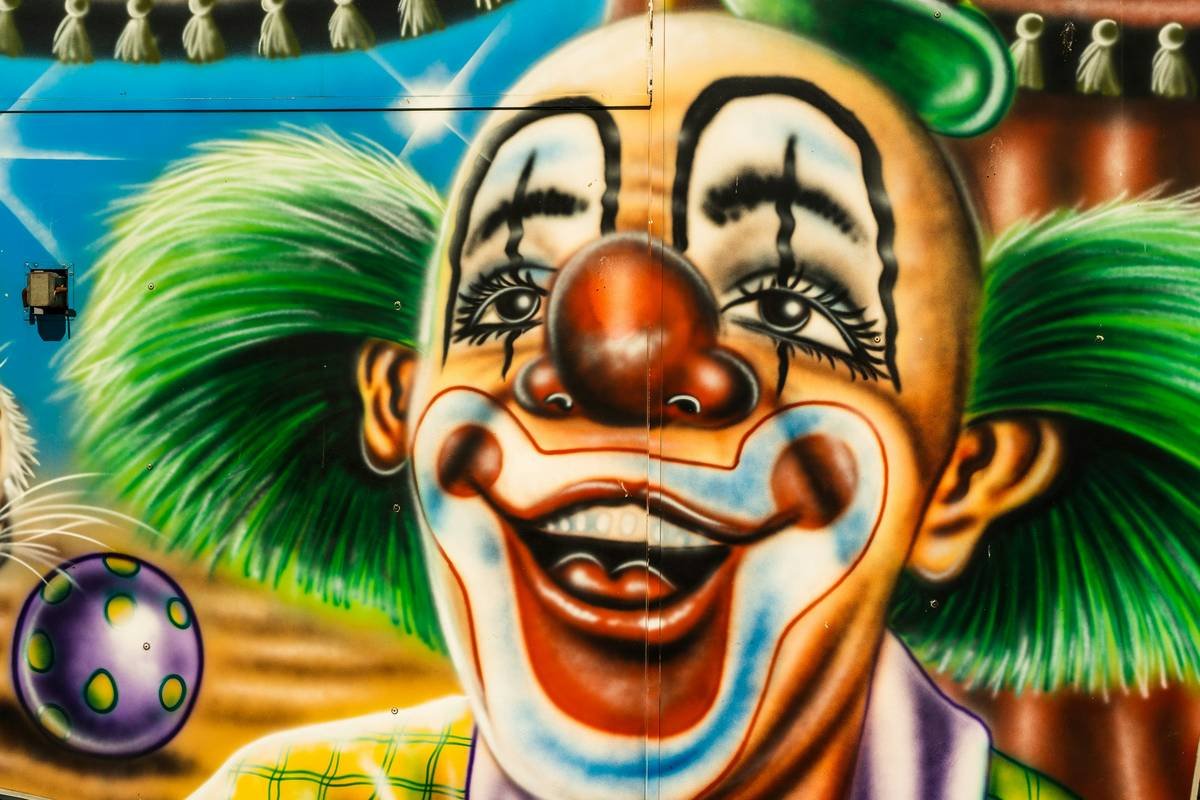 Professional clown costume cosmetics applied on model with bold white base, red cheeks, and defined black accents