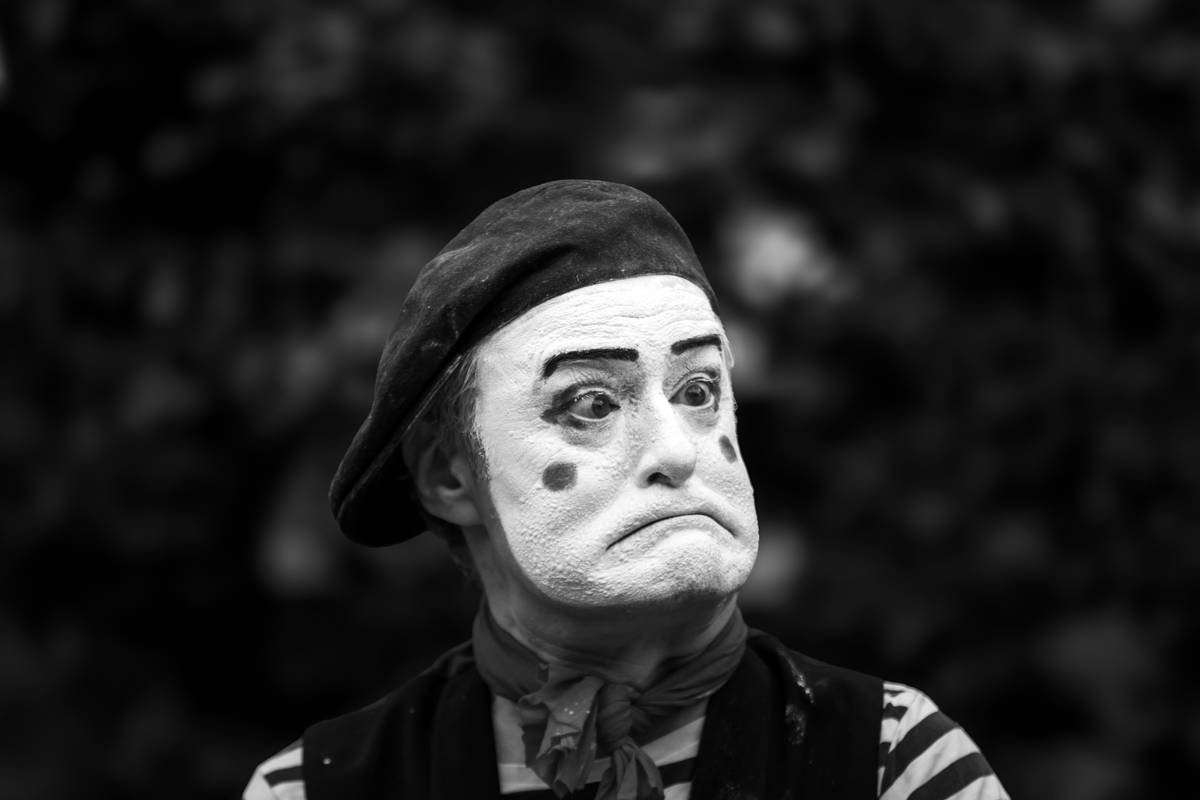 Professional artist applying mime costume makeup with sponge, showing seamless white base on model's face