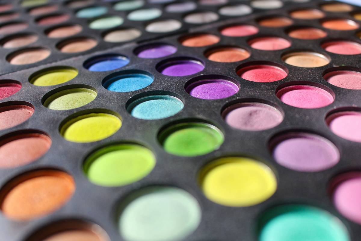 Professional costume makeup palettes displayed open with brushes and sponges on a clean black surface